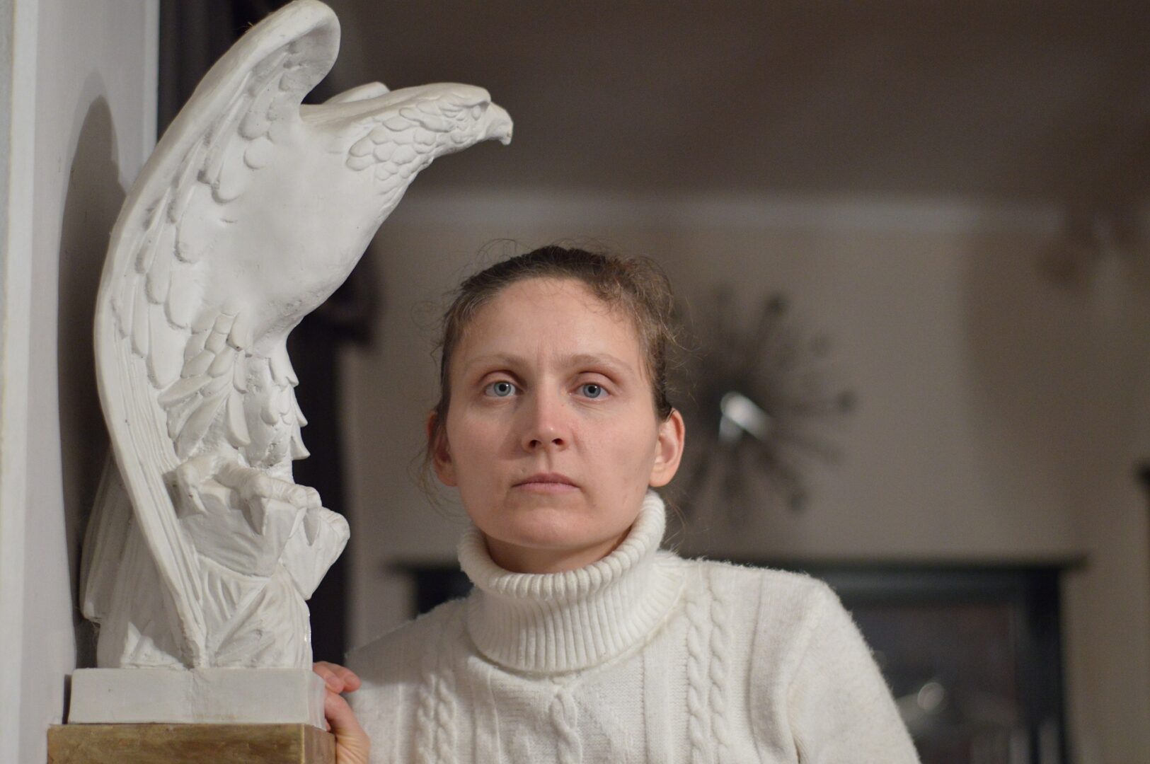 Woman beside white eagle sculpture indoors.